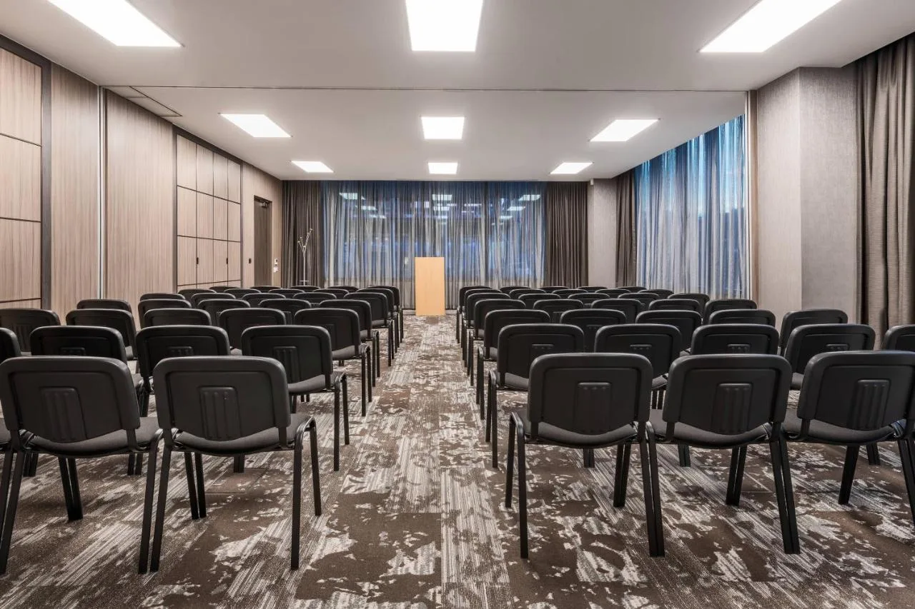 an empty conference room with chairs and a podium at AC Hotel by Marriott Manchester City Centre in Manchester
